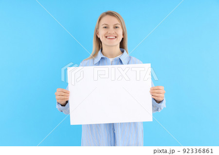 Woman holds blank banner on blue background 92336861