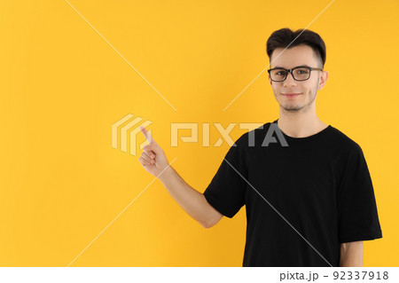 Young man in glasses on yellow background 92337918