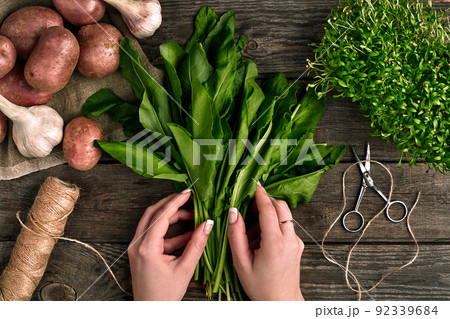 Woman hands holding fresh organic spinach leaves. Vegetables, onion, garlic, potatoes, spinach, lettuce leaves on wooden background Woman hands holding fresh organic spinach leaves. Vegetables, onion, garlic, potatoes, spinach, lettuce leaves on wooden background 92339684