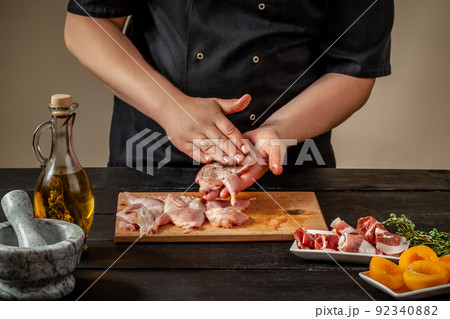 The chef prepares raw quail carcasses in the kitchen. Fresh raw meat quails ready for cooking on the wooden board The chef prepares raw quail carcasses in the kitchen. Fresh raw meat quails ready for cooking on the wooden board 92340882
