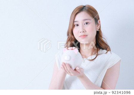 貯金箱を持つ若い女性｜カメラ目線 92341096