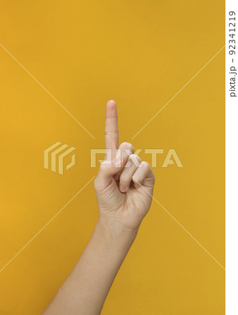 Woman hand shows index finger up on yellow background Woman hand shows index finger up on yellow background 92341219