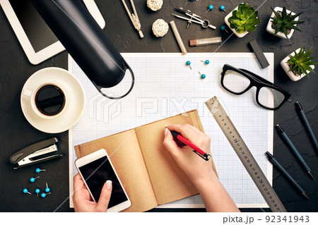 Concept architects. Architects workplace, architectural project, blueprints, ruler. Engineer holds a pen and writes in a notebook. Equipment architects on the desk with a blueprint in the office. Concept architects. Architects workplace, architectural project, blueprints, ruler. Engineer holds a pen and writes in a notebook. Equipment architects on the desk with a blueprint in the office. 92341943