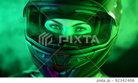 Young female motorcyclist woman in closed motorcycle helmet. Driver biker looking to camera under 92342406