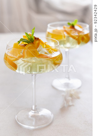 Transparent cocktail with ice cubes in a glass decorated with slices of orange close up 92342429