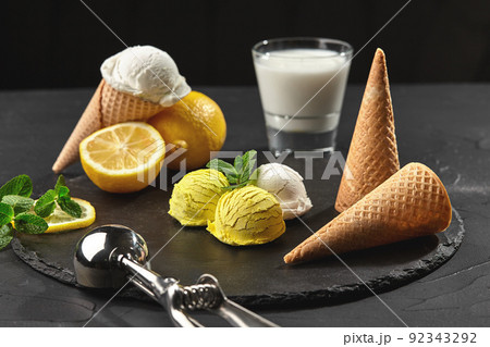 Tasty creamy and citrus lemon ice cream decorated with mint served on a stone slate over a black background. 92343292