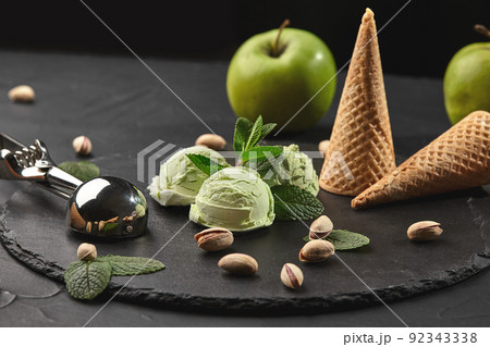 Gourmet pistachio ice cream served on a stone slate over a black background. Gourmet pistachio ice cream served on a stone slate over a black background. 92343338