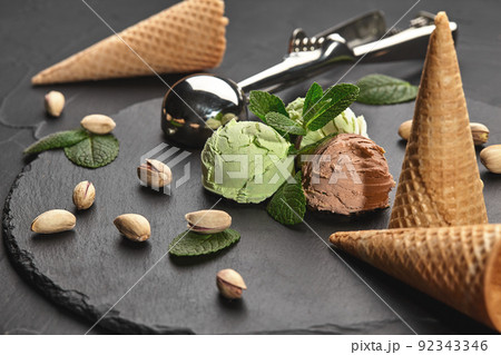 Gourmet chocolate and pistachio ice cream served on a stone slate over a black background. 92343346