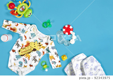 Babies goods: cloth diaper, baby powder, nibbler, cream, teether, soother, baby toy on blue background. Copy space. Top view. Babies goods: cloth diaper, baby powder, nibbler, cream, teether, soother, baby toy on blue background. Copy space. Top view. 92343975