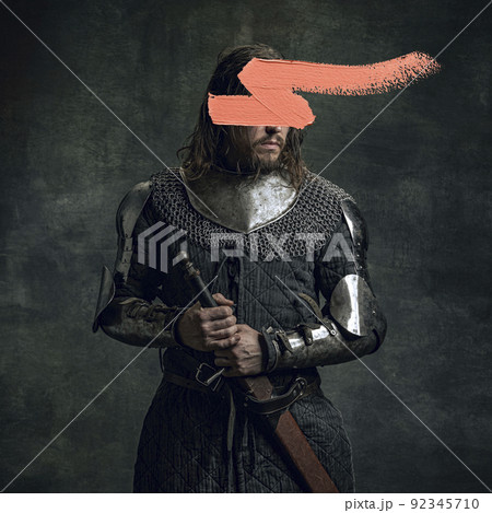 Artwork. Young man as medieval warrior, knight isolated on dark vintage background. Random stroke of pink paint on his face. Art, creativity, eras comparison concept. 92345710