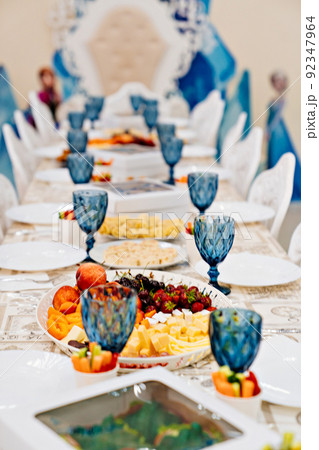 a large festive table with appetizers and glasses of blue glass. 92347964