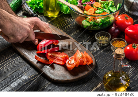 Man's hands cutting red paprika with knife. Cook cut red paprika. Man loves cooking fresh salad for dinner. Paprika cut by cook's hand. Man's hands cutting red paprika with knife. Cook cut red paprika. Man loves cooking fresh salad for dinner. Paprika cut by cook's hand. 92348430
