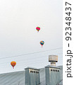 Multicolored balloons fly in the sky above the metal roof of a house, vertical photo 92348437
