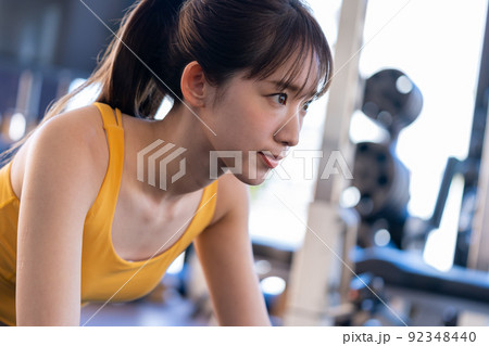 スポーツジムでトレーニングする若い女性 92348440
