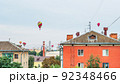 Many colorful balloons fly in the sky above the roofs of high-rise buildings in a provincial city 92348466