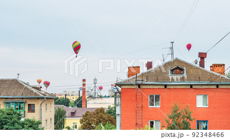 Many colorful balloons fly in the sky above the roofs of high-rise buildings in a provincial city Many colorful balloons fly in the sky above the roofs of high-rise buildings in a provincial city 92348466