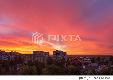 Bright coral sky before dawn in a provincial residential area of the city with high-rise buildings. Cityscape. Bright coral sky before dawn in a provincial residential area of the city with high-rise buildings. Cityscape. 92348498