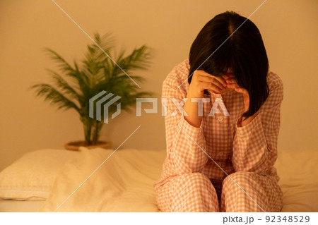 寝室で落ち込むパジャマ姿のミドル女性 92348529