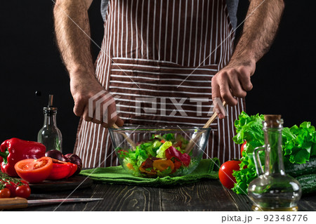 Man preparing salad with fresh vegetables on a wooden table. Cooking tasty and healthy food 92348776