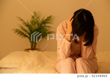 寝室で落ち込むパジャマ姿のミドル女性 92348969