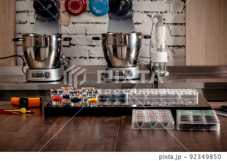 Confectionery and cooking tools for sweets on wooden table. Plastic moulds, mixers, food colors, measuring cups. 92349850