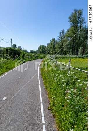 A neatly 2 lane asphalted cycle path along the meadows of Sassenheim in the Netherlands. 92350662
