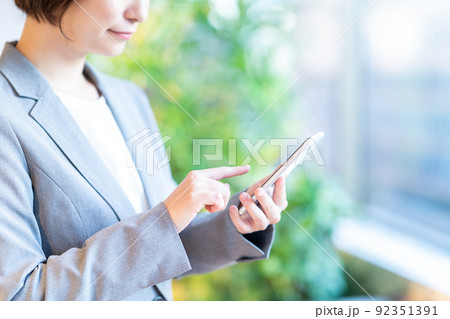 オフィスの窓際でスマホを操作する女性（パーツ） 92351391