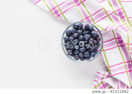 Blueberries in glass bowl on white background with kitchen cloth towel, concept of healthy eating vegan food and snack. Top view, copy space Blueberries in glass bowl on white background with kitchen cloth towel, concept of healthy eating vegan food and snack. Top view, copy space 92352882