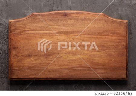 Wooden nameplate or sign board screwed at wall background. Front view of name plate 92356468