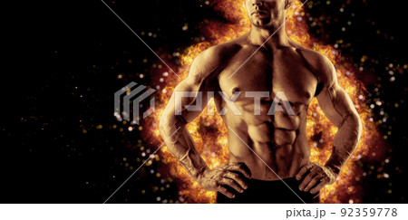 Brutal strong athletic Bodybuilder posing. Fire and spark explosion in the background. 92359778