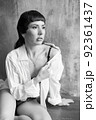 A sensual portrait of a girl with an emotional face and sensual eyes in a white shirt. 92361437