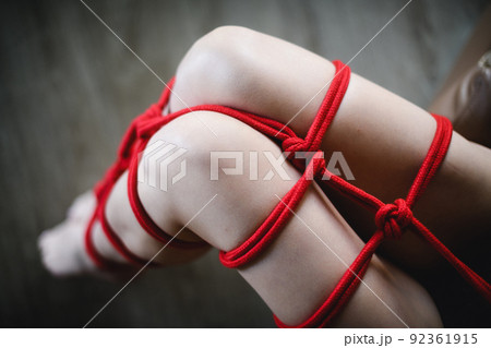 Female legs are tied with red rope. Female legs are tied with red rope. 92361915