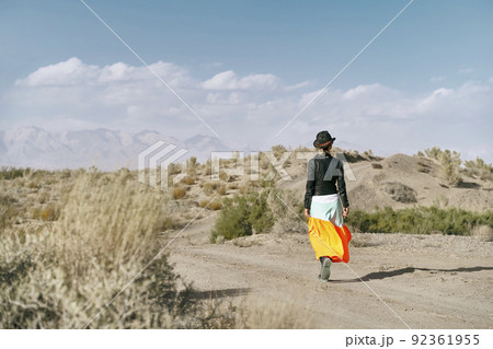 rear view of an asian woman in long skirt walking on a dirt road through gobi desert rear view of an asian woman in long skirt walking on a dirt road through gobi desert 92361955