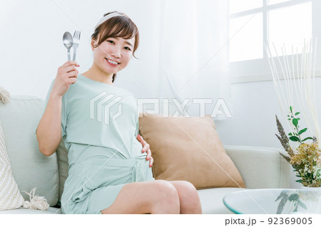 スプーンとフォークを持つ日本人の妊婦（大食い・食事） 92369005