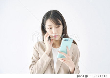 スマホを見て悩むビジネスウーマン　白バック 92371318