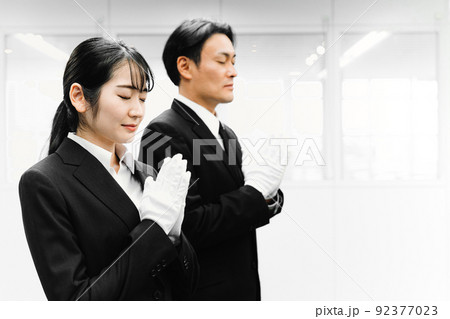 白手袋をつけて合掌するスーツ姿の男女（葬祭ディレクター・お葬式） 92377023