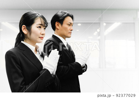 白手袋をつけて合掌するスーツ姿の男女（葬祭ディレクター・お葬式） 92377029