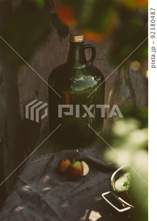 A large bottle of fruit cider on a rustic table with a harvest of pears, on an autumn sunny day A large bottle of fruit cider on a rustic table with a harvest of pears, on an autumn sunny day 92380487