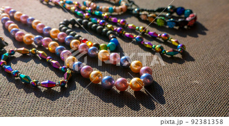Heap of colored bright jewelry beads on a dark background. Different gems beads necklace. Jewel necklace modern fashion pattern or texture. jewellery background Heap of colored bright jewelry beads on a dark background. Different gems beads necklace. Jewel necklace modern fashion pattern or texture. jewellery background 92381358