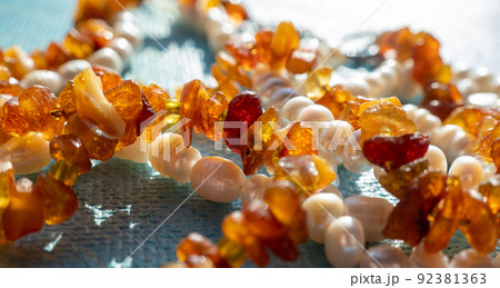 Sunny beads of amber pearl lapis lazuli on blue backgroung. Natural sea gemstone sunlight background, jewelry concept Sunny beads of amber pearl lapis lazuli on blue backgroung. Natural sea gemstone sunlight background, jewelry concept 92381363