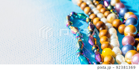 Heap of colored bright jewelry beads on a blue background. Different gems beads necklace. Jewel necklace modern fashion pattern or texture. copy space. 92381369