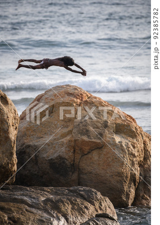 Cliff jumper at Galle fort, brave and dangerous jump perform by the local boy. Acrobatic jump off. Cliff jumper at Galle fort, brave and dangerous jump perform by the local boy. Acrobatic jump off. 92385782