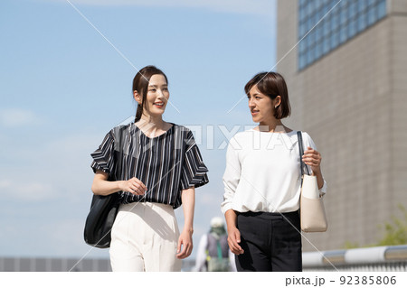 青空の下を歩く2人のビジネスウーマン 青空の下を歩く2人のビジネスウーマン 92385806