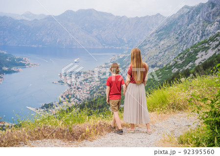 Mother and son travellers enjoys the view of Kotor. Montenegro. Bay of Kotor, Gulf of Kotor, Boka Kotorska and walled old city. Travel to Montenegro concept. Fortifications of Kotor is on UNESCO World 92395560