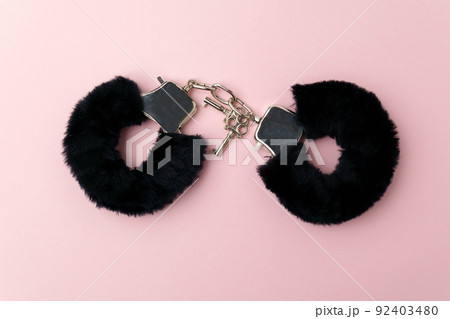 Black fluffy handcuffs. Erotic sex game with sexual bdsm toy. Pink background 92403480