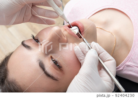 Dental check up in dential clinic. Dentist examining patient teeth with dental mirror during dental check up Dental check up in dential clinic. Dentist examining patient teeth with dental mirror during dental check up 92404230