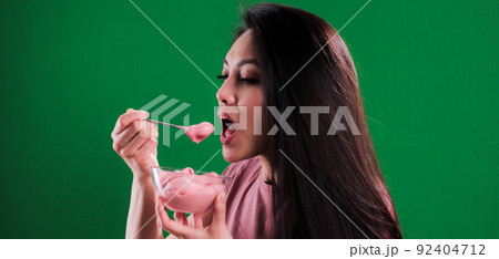 Young happy woman enjoys her bowl of ice cream 92404712