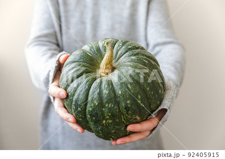 Autumnal Background. Unrecognizable woman hand holding in hands autumn fall pumpkin isolated on white background. Change of seasons ripe organic food, Halloween party Thanksgiving day Autumnal Background. Unrecognizable woman hand holding in hands autumn fall pumpkin isolated on white background. Change of seasons ripe organic food, Halloween party Thanksgiving day 92405915