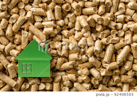 Small green house over wood pellets background. Small green house over wood pellets background. 92406503