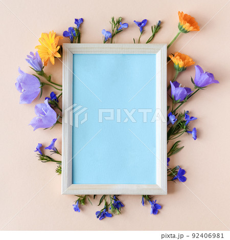 Blue bluebell, lobelia flowers and orange calendula flowers with a blue text frame on an orange background. Summer flat lay 92406981